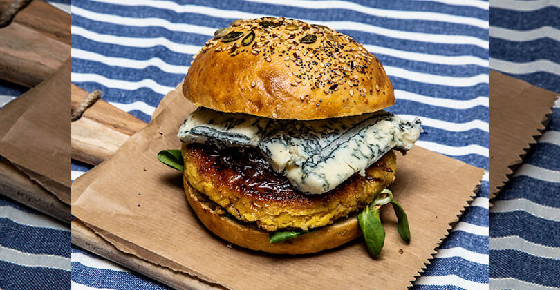 Chickpea hamburger with salad, crumbled spicy Gorgonzola PDO and caramelised red onions - Gorgonzola